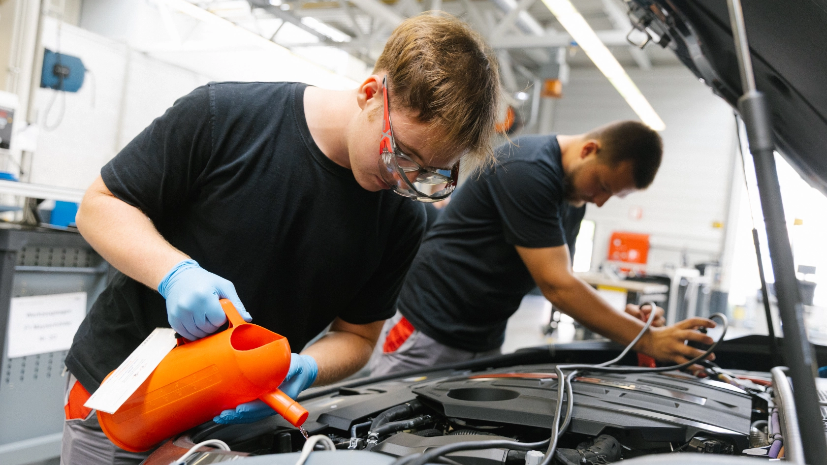 Zwei Auszubildende bei Audi in Neckarsulm füllen das Scheibenwischwasser nach.
